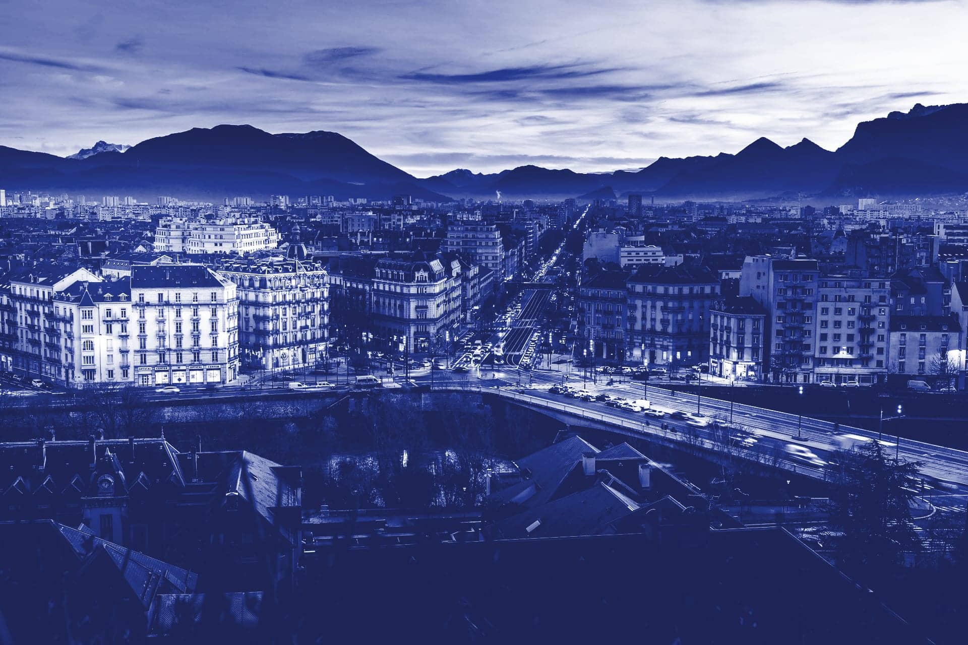 Immeubles de l’agglomération grenobloise au crépuscule, montagnes au fond